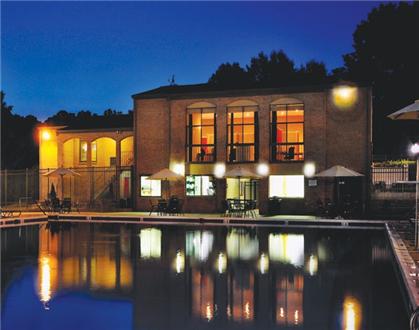 Sparkling pool with clubhouse exterior Sparkling pool with clubhouse exterior